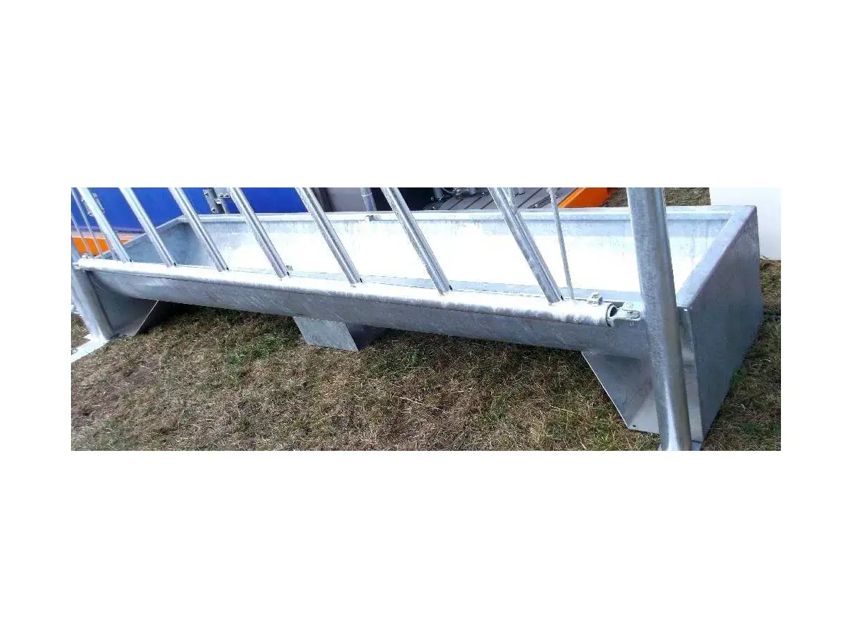 Metalowy żłób na paszę dla zwierząt, stojący na trawie. Solidna konstrukcja zapewnia wygodne karmienie.