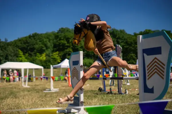 Dziewczynka na kucyku z patyka przeskakuje przez przeszkodę. Czy hobby horse to sport? Z pewnością wymaga zwinności i determinacji!