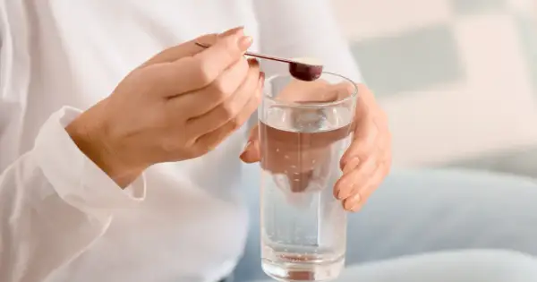 Kobieta dodaje proszek do szklanki wody. Czy kolagen dla koni mogą przyjmować ludzie?